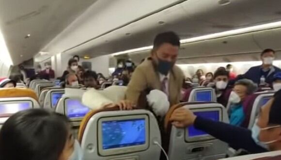 El asistente de vuelo agarró con fuerza a una mujer que había tosido a una azafata. (YouTube: Fugu M)