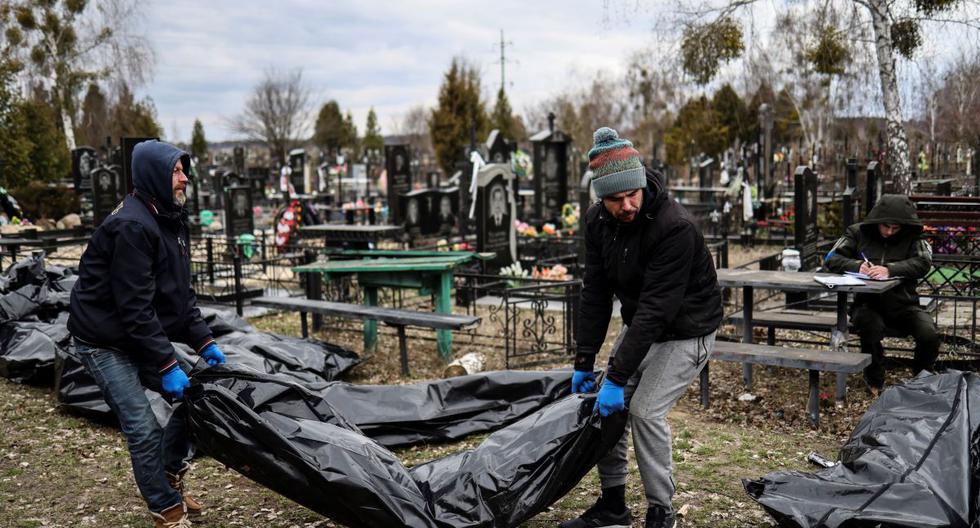 Los trabajadores alinean los cuerpos para que los identifique el personal forense y los agentes de policía en el cementerio de Bucha, al norte de Kiev, el 6 de abril de 2022. (RONALDO SCHEMIDT / AFP).