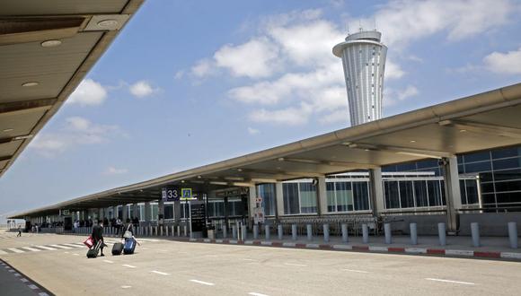 Los pasajeros que salen enrollan sus maletas en el aeropuerto Ben Gurion casi desierto en Lod, cerca de la ciudad costera israelí de Tel Aviv, el 13 de mayo de 2021. (GIL COHEN-MAGEN / AFP).