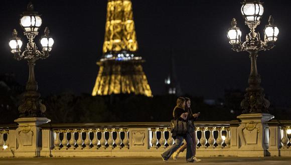 Dos peatones caminan por el puente Alexandre III poco antes del toque de queda nocturno por coronavirus en París (Francia), el 23 de octubre de 2020. (EFE/EPA/IAN LANGSDON).