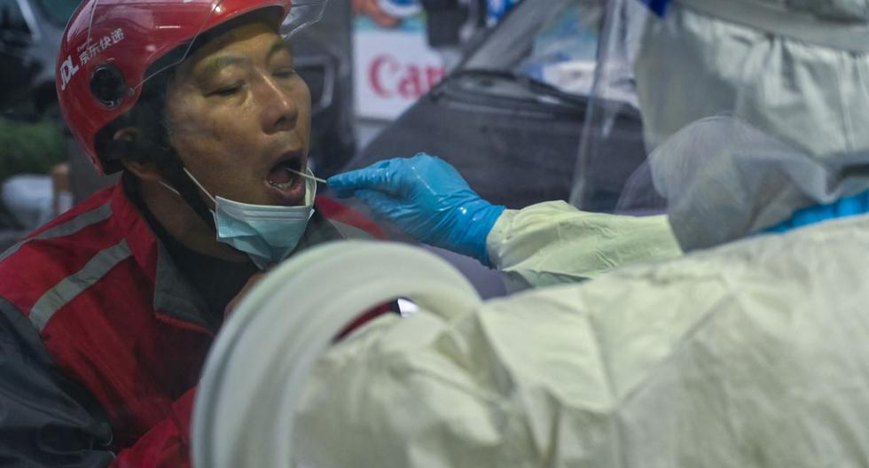 Un trabajador de la salud toma una muestra de hisopo de una mujer para detectar el coronavirus Covid-19 en el distrito de Huangpu, en Shanghai, China, el 8 de diciembre de 2022. (Héctor RETAMAL / AFP).