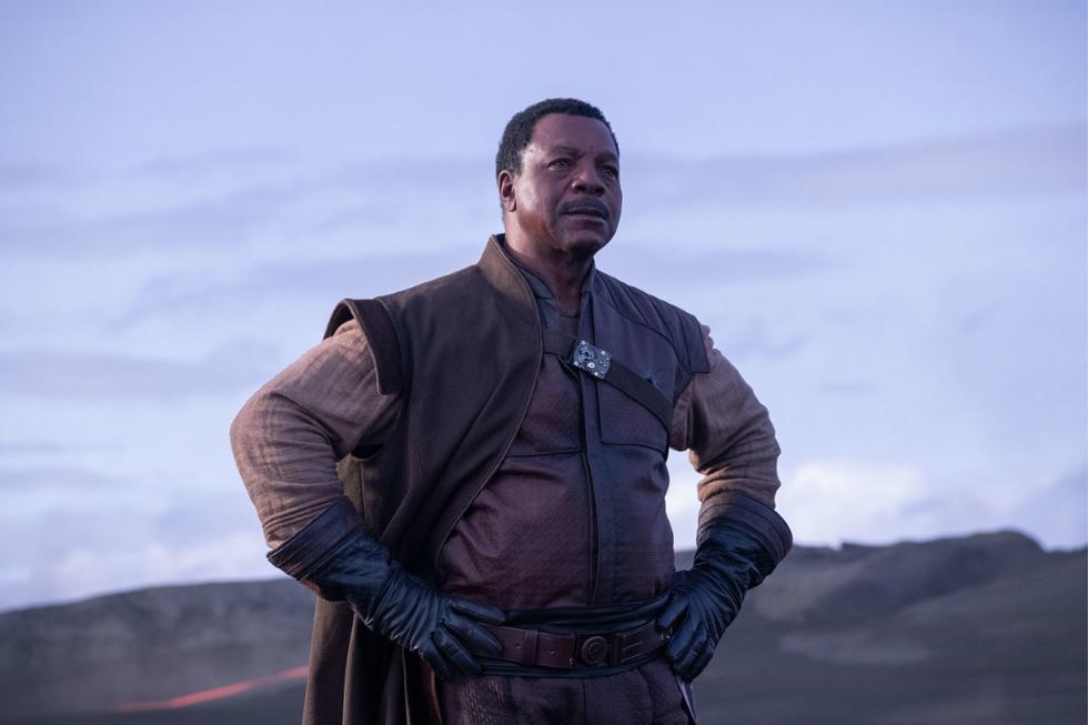 Cuando Carl Weathers se sumó a <b>The Mandalorian</b> no esperaba tener mucho tiempo en escena como Greef Karga. <i>“Lo enganchamos”</i>, se ríe Jon Favreau. <i>“Comenzamos diciéndole: ‘Oye, tal vez, puedas hacer algunos episodios’. Y eso se convirtió en: ‘¿Sabes? Realmente nos gusta tu personaje…’. Lo incluimos en la serie mucho más de lo que él había aceptado. Y ahora en la segunda temporada dirige para nosotros, ya que Carl ha estado en este set innovador y de alta tecnología que desarrollamos para estas historias específicas, ha visto cómo armamos esto. Nos ha visto experimentando con él y ha visto cómo todo se va armando, así que está perfectamente calificado. Él entiende la historia. Entiende a los personajes, así como al elenco y la tecnología. Es muy divertido estar trabajando con Carl”</i>. | Crédito: Disney.