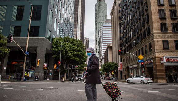 Una mujer con una máscara camina en el centro de Los Ángeles durante la emergencia por el brote de coronavirus (COVID-19) (Foto: AFP)