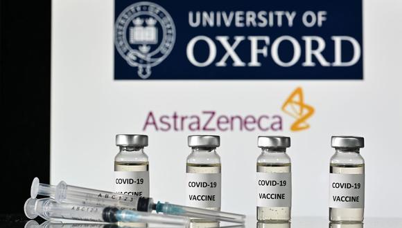 Esta foto de ilustración tomada el 17 de noviembre de 2020 muestra viales con adhesivos de vacuna COVID-19 y jeringas, con el logotipo de la Universidad de Oxford y su compañía farmacéutica británica asociada AstraZeneca.  (JUSTIN TALLIS / AFP).