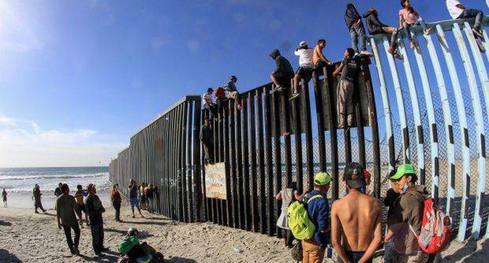 Integrantes de la caravana de centroamericanos escalan el muro fronterizo en Tijuana, en el estado de Baja California (México), el pasado martes. (Foto: EFE)