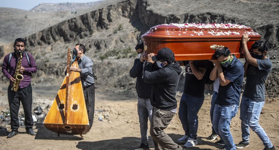 Familiares cargan el ataúd de una presunta víctima de coronavirus mientras los músicos tocan en el cementerio de Nueva Esperanza, uno de los más grandes de América Latina, ubicado en el sur de Lima, Perú. (Foto: ERNESTO BENAVIDES / AFP).