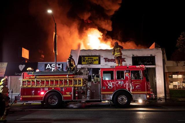 Los bomberos de Los Ángeles luchan contra el fuego en un negocio incendiado durante el toque de queda que siguió a las violentas protestas por el asesinato de George Floyd. (EFE/EPA/ETIENNE LAURENT).