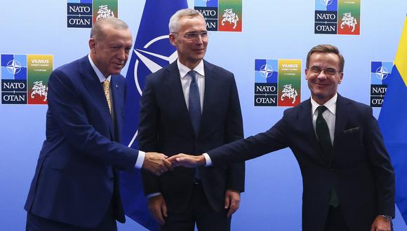 El presidente turco, Tayyip Erdogan, y el primer ministro sueco, Ulf Kristersson, se dan la mano junto al secretario general de la OTAN, Jens Stoltenberg, antes de su reunión, en vísperas de una cumbre de la OTAN, en Vilnius el 10 de julio de 2023. (Foto de YVES HERMAN / POOL / AFP )