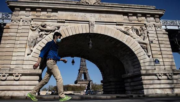 Un peatón que usa mascarilla para protegerse del coronavirus camina por el puente Bir Hakeim, cerca de la Torre Eiffel, en París, Francia. (Foto: EFE / EPA / IAN LANGSDON).