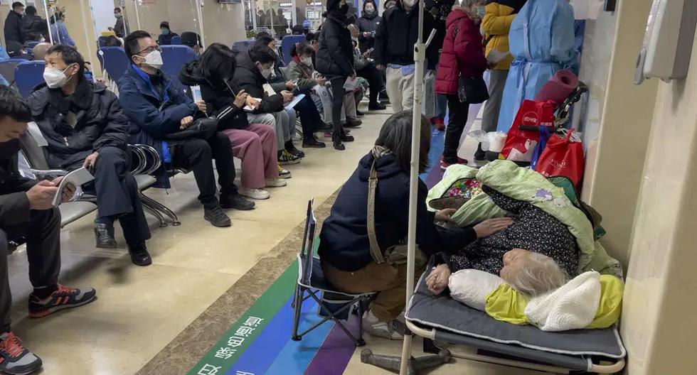 Una mujer cuida a un familiar mayor tendido en una camilla mientras recibe un tratamiento intravenoso en un hospital de Beijing, China, el 5 de enero de 2023. (AP Foto/Andy Wong).