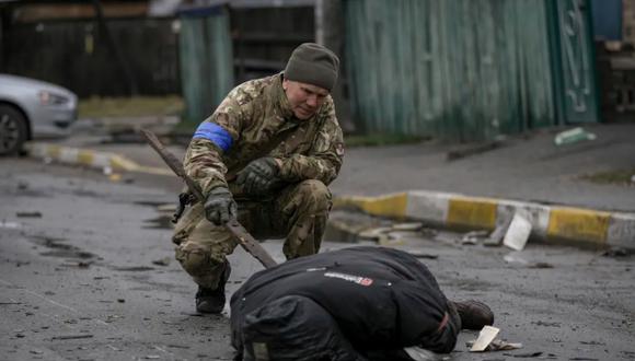 Un militar revisa el cuerpo de un civil en Bucha