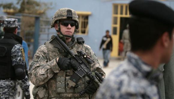 Un soldado estadounidense asegura una calle junto con soldados iraquíes mientras esperan la llegada de un cargamento de ropa deportiva donada desde los Estados Unidos para niños iraquíes en el barrio de Abu Sheer en el distrito sureño de Dura en Bagdad. (Foto: AHMAD AL-RUBAYE / AFP).