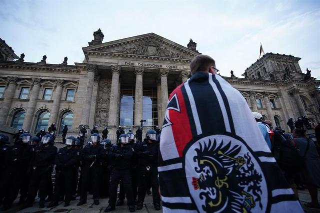 Manifestantes se paran frente al edificio del Reichstag después de intentar subir las escaleras durante una protesta contra las regulaciones para frenar la pandemia de coronavirus en Alemania. (EFE / EPA / CLEMENS BILAN).