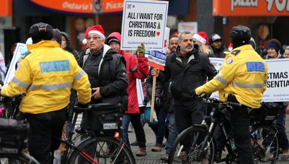 Un grupo desenmascarado participa durante un desfile de Santa Claus en protesta contra las restricciones de la enfermedad del coronavirus (COVID-19), en lo que la policía de Toronto describió como una reunión no autorizada por la ciudad en Toronto, Ontario, Canadá. (Foto: REUTERS / Chris Helgren).
