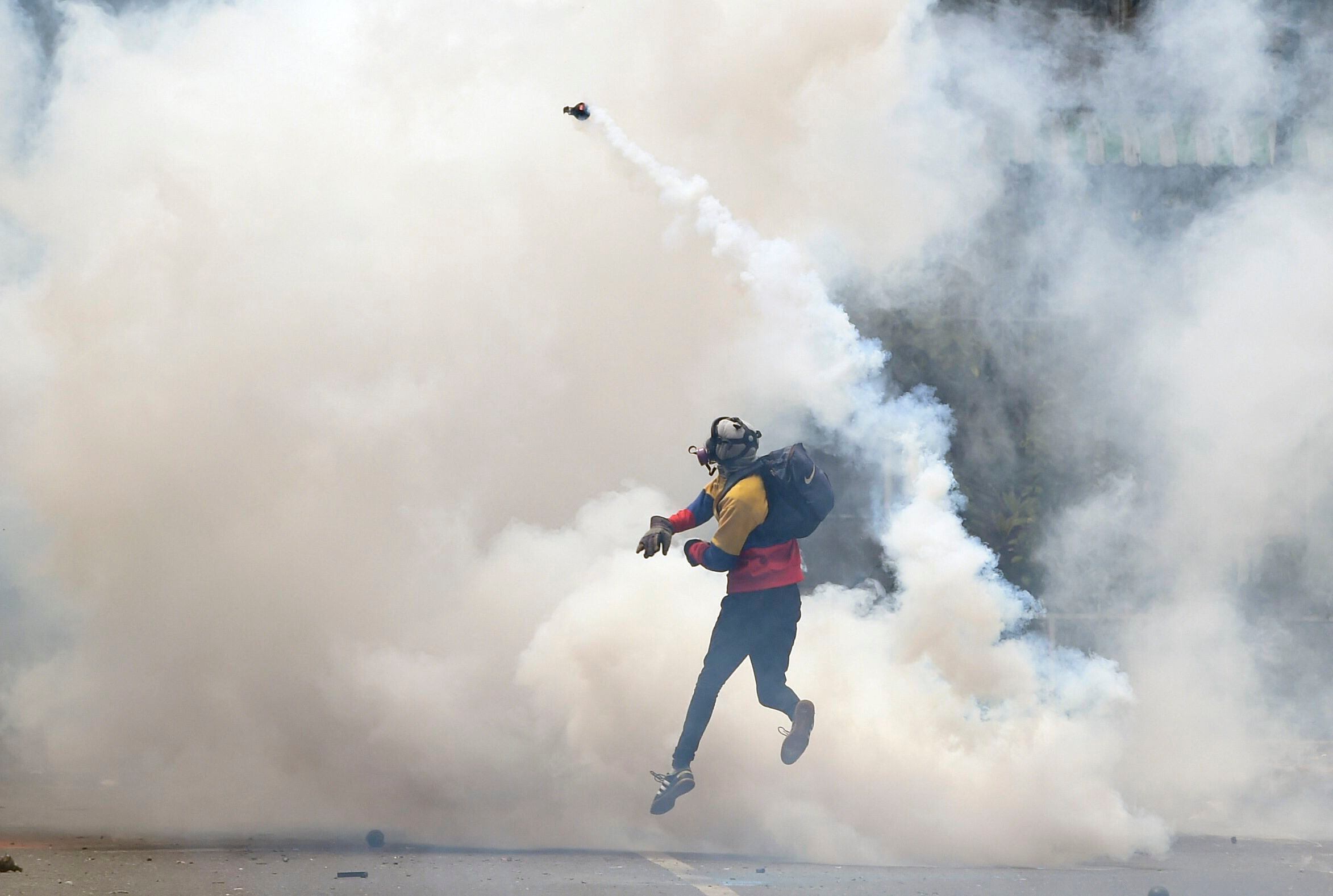 An opposition activist returns tear gas to police as clashes erupt during a protest against President Nicolás Maduro on May 8, 2017. (Photo by JUAN BARRETO/AFP).
