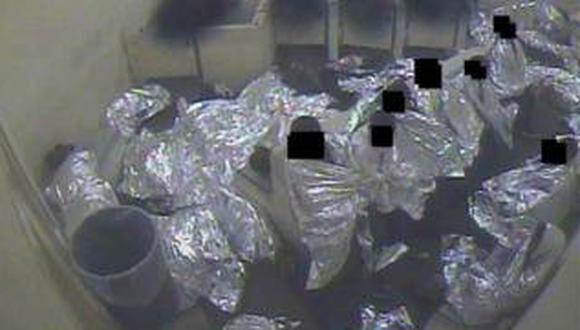 Una imagen tomada de un video sin fecha muestra a un grupo de hombres arropados con mantas isotérmicas en una celda de la Patrulla Fronteriza en Tucson, Arizona.