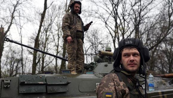 Los soldados ucranianos se paran junto a su transporte blindado de personal (APC), no lejos de la línea del frente con las tropas rusas, en el distrito de Izyum, región de Kharkiv, el 18 de abril de 2022, durante la invasión rusa de Ucrania. (Anatolii Stepanov / AFP).