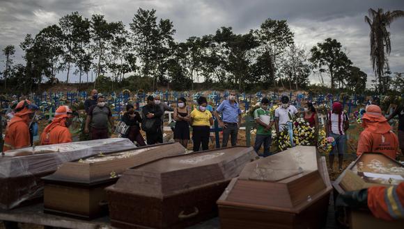 Un grupo de personas asiste a un sepelio en una tumba colectiva, en un área abierta en el cementerio Nossa Senhora Aparecida, ubicado en la ciudad de Manaos, Amazonas. La nueva sección del cementerio se abrió después de las muertes causadas por el coronavirus. (EFE / Raphael Alves).