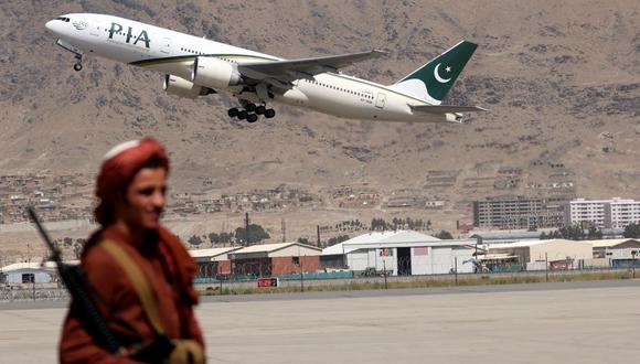 Un combatiente talibán monta guardia mientras un avión de Pakistan International Airlines, el primer vuelo comercial internacional en aterrizar desde que los talibanes recuperaron el poder el mes pasado, despega con pasajeros a bordo en el aeropuerto de Kabul el 13 de septiembre de 2021. (Karim SAHIB / AFP).