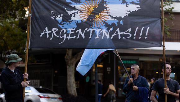 Hombres sostienen una bandera que representa el mapa de las islas Malvinas/Falklands que dice "¡Argentina!" durante una protesta frente a la embajada de Gran Bretaña en Buenos Aires, el 2 de abril de 2022.  (Foto de Tomás CUESTA / AFP)