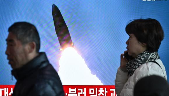 La gente pasa junto a un televisor que muestra una transmisión de noticias con imágenes de archivo de una prueba de misiles de Corea del Norte en una estación de tren en Seúl el 18 de marzo de 2024. (Foto de Anthony WALLACE / AFP).