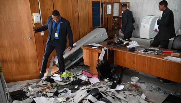 Hombres revisan los daños causados en una oficina destrozada al interior del Palacio de Planalto luego de que manifestantes bolsonaristas tomaran la víspera las sedes de los tres poderes del Estado.