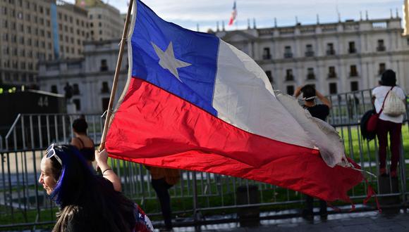 Una manifestante lleva una bandera cerca del palacio presidencial de La Moneda.(AFP / Martin BERNETTI).