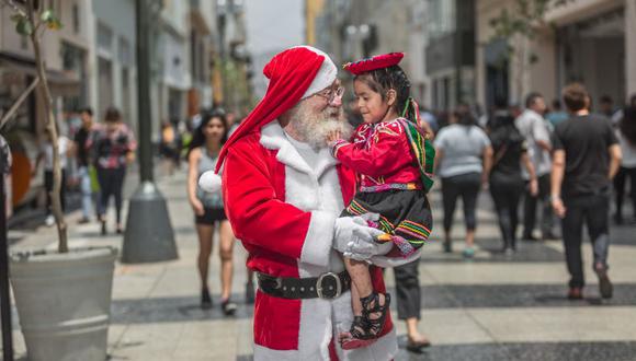 Genaro Aldón (73), conocido como el Papa Noel Mágico, le pide a la pequeña Aracely (3) su lista de deseos. Su madre, una vendedora en el Centro de Lima, dice que quiere muñecas.