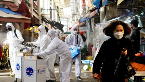 Una mujer cubierta por una mascarilla sale de un mercado que será fumigado por una compañía que ofrece servicios de desinfección en Seul, capital de Corea del Sur. El rociado de  desinfectante es parte de las medidas preventivas contra la propagación del coronavirus. (Reuters)