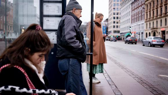 Las personas esperan en una parada de autobús en Copenhague el 1 de febrero de 2022, cuando Dinamarca se convierte en el primer país de la Europa en levantar las restricciones por el coronavirus. (LISELOTTE SABROE / RITZAU SCANPIX / AFP).