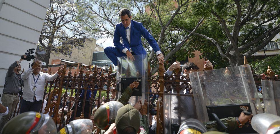 Juan Guaidó trepa una reja para intentar entrar a la Asamblea Nacional de Venezuela. (AP Photo/Matias Delacroix).