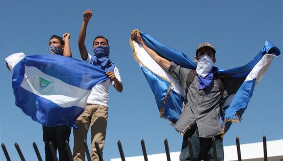 Manifestantes de oposición gritan consignas desde un centro comercial donde se refugiaron después de que la policía antidisturbios de Nicaragua les impidió manifestarse contra el gobierno. (Foto: AFP)