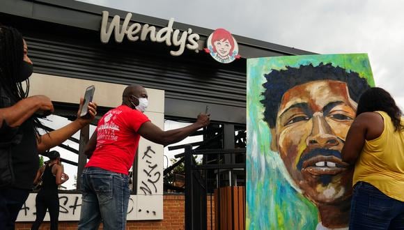 un muralista que pinta la cara de Rayshard Jones afuera de un restaurante Wendy's quemado el segundo día después de que la policía lo matara a tiros en el estacionamiento del restaurante el 14 de junio de 2020 en Atlanta, Georgia. (Foto de Elijah Nouvelage / AFP)