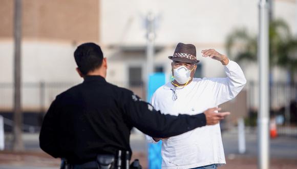 Un oficial de policía habla con un hombre que lleva una mascarilla como medida preventiva contra el coronavirus. (Foto: AFP)