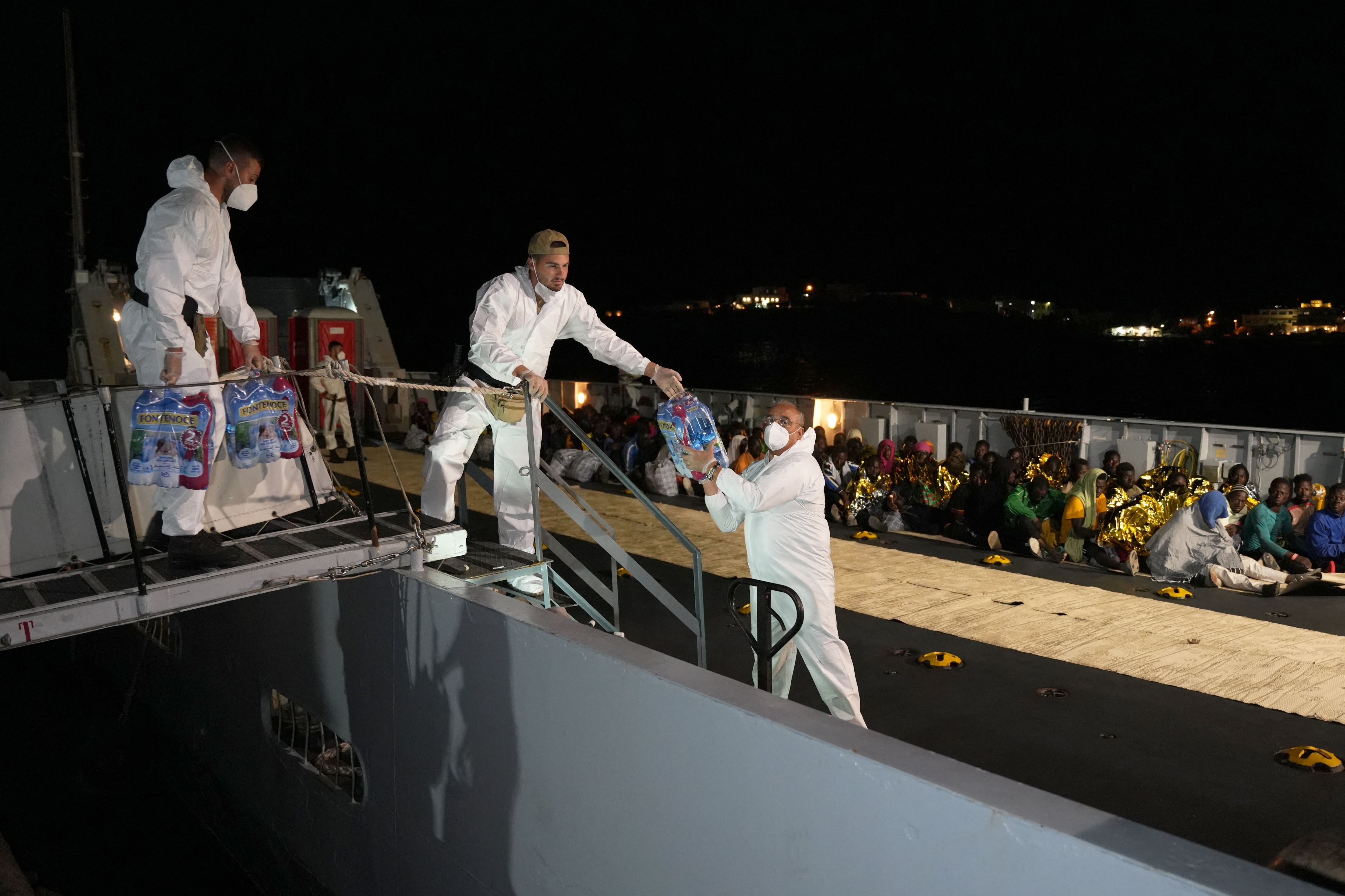 Authorities hand out bottles of water to migrants sitting on the deck of a rescue ship in the port on the Italian island of Lampedusa, September 16, 2023. (Photo: AFP)