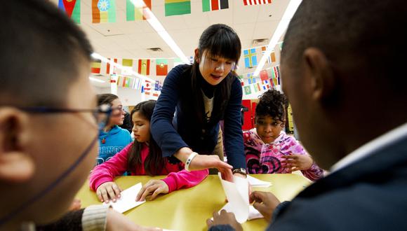 La maestra de escuela japonesa Haruna Konno (C) de la escuela elemental de Fukuoka, ayuda a los niños de la escuela estadounidense a hacer un origami después de la parte de aprendizaje de la experiencia de la clase escolar donde los niños escucharon sobre el 11 de marzo de 2011, Japón, (Foto de PAUL J. RICHARDS / AFP )