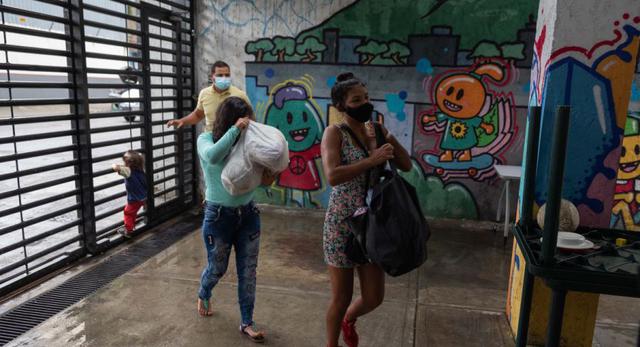 Dos mujeres cargan bolsas con donativos en los espacios de la ONG Otro Enfoque este viernes, en Caracas (Venezuela). (EFE/RAYNER PEÑA R.).