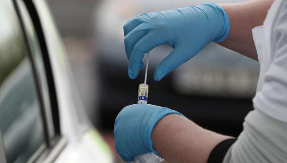 A medical worker holds a sample as she tests a key worker for the novel coronavirus Covid-19 at a drive-in testing centre at Glasgow Airport on April 29, 2020, as the UK continues in lockdown to help curb the spread of the coronavirus. (Photo by Andrew Milligan / POOL / AFP)
