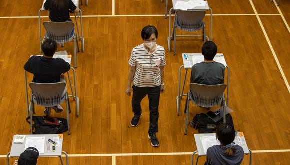 Un vigilante (C) verifica a los estudiantes de secundaria que toman los exámenes del Diploma de Educación Secundaria de Hong Kong (HKDSE) en la Escuela Secundaria Creativa en Hong Kong el 22 de abril de 2022. (Foto de Jerome FAVRE / POOL / AFP)