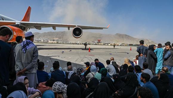 Los afganos se sientan mientras esperan salir del aeropuerto de Kabul, la capital de Afganistán, el 16 de agosto de 2021. (Wakil Kohsar / AFP).