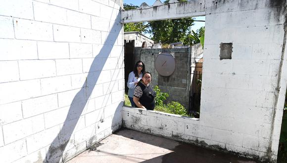 La ministra de Vivienda Michelle Sol (I) con Ana Vilma Cuéllar, mujer que compró una casa hace 20 años pero nunca vivió ahí por temor a pandillas en La Campanera, municipio de Soyapango, El Salvador, el 13 de enero de 2023 . (Foto de Marvin RECINOS / AFP)