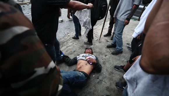 Manifestantes socorren a un herido durante los enfrentamientos con la policía a los alrededores de la Casa de la Cultura en Quito, Ecuador. (EFE/ José Jácome).