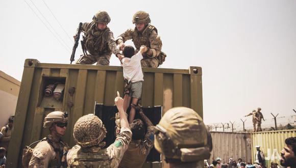 En esta imagen, cortesía del Departamento de Asuntos Públicos del Comando Central de Estados Unidos, las fuerzas de la coalición ayudan a un niño durante una evacuación en el Aeropuerto Internacional Hamid Karzai en Kabul. (Foto: Victor MANCILLA / Asuntos Públicos del Comando Central de EE. UU. / AFP).