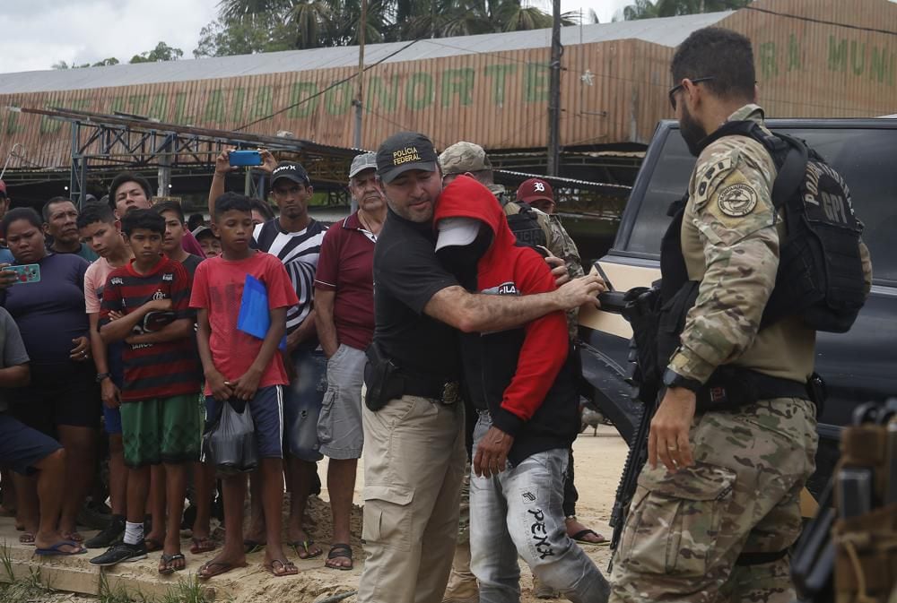A federal police officer escorts a suspect towards a river in the area where indigenous expert Bruno Araújo Pereira and freelance British journalist Dom Phillips disappeared.  (AP Photo/Edmar Barros)