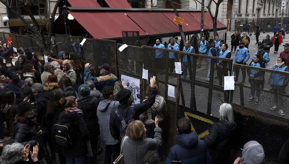 Policías al otro lado de una valla de seguridad cerca a la Legislatura de la Ciudad de Buenos Aires el 4 de septiembre de 2023, mientras manifestantes protestan contra un evento organizado por Victoria Villaruel. (Foto de Juan MABROMATA / AFP)