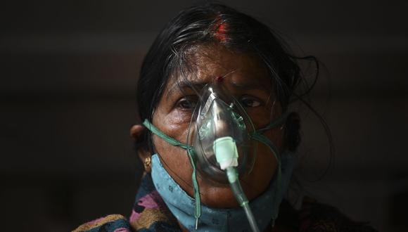 Una paciente respira con la ayuda de oxígeno en una carpa instalada a lo largo de la carretera en medio de la pandemia del coronavirus Covid-19 en Ghaziabad, India, el 2 de mayo de 2021 (Foto de Sajjad HUSSAIN / AFP).
