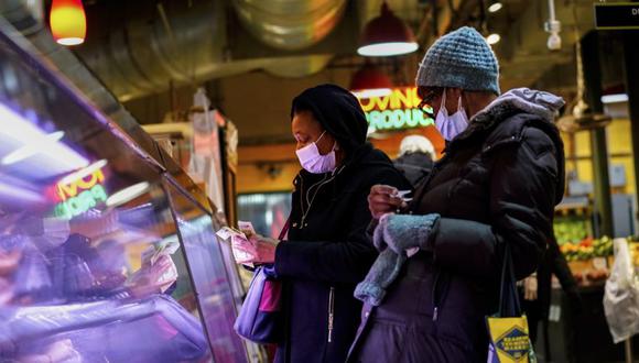 Los clientes usan máscaras faciales para protegerse contra la propagación del coronavirus mientras compran en el Reading Terminal Market en Filadelfia.