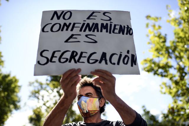 Un manifestante sostiene un cartel que dice "No es confinamiento, es segregación" durante una manifestación contra las restricciones impuestas por el gobierno regional para combatir la propagación del coronavirus en el distrito de Vallecas, en Madrid. (Foto de OSCAR DEL POZO / AFP).