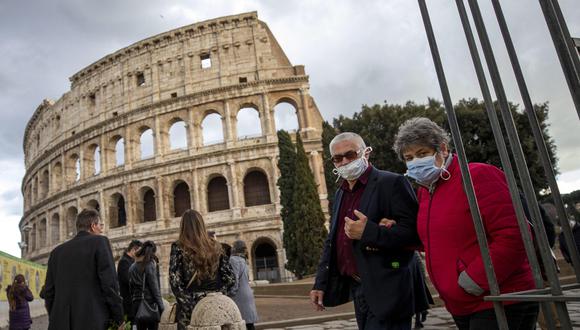Los turistas usan máscaras faciales mientras caminan cerca del Coliseo en Roma, Italia, el segundo país con más muertes por coronavirus. (EFE / EPA / MASSIMO PERCOSSI).