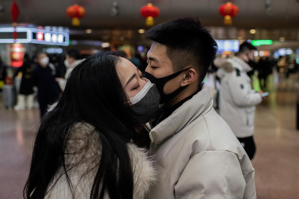 Una pareja, provista de mascarillas, se dan un beso de despedida en la estación de tren de Beijing, China, en enero de este año. (Photo by NICOLAS ASFOURI / AFP)